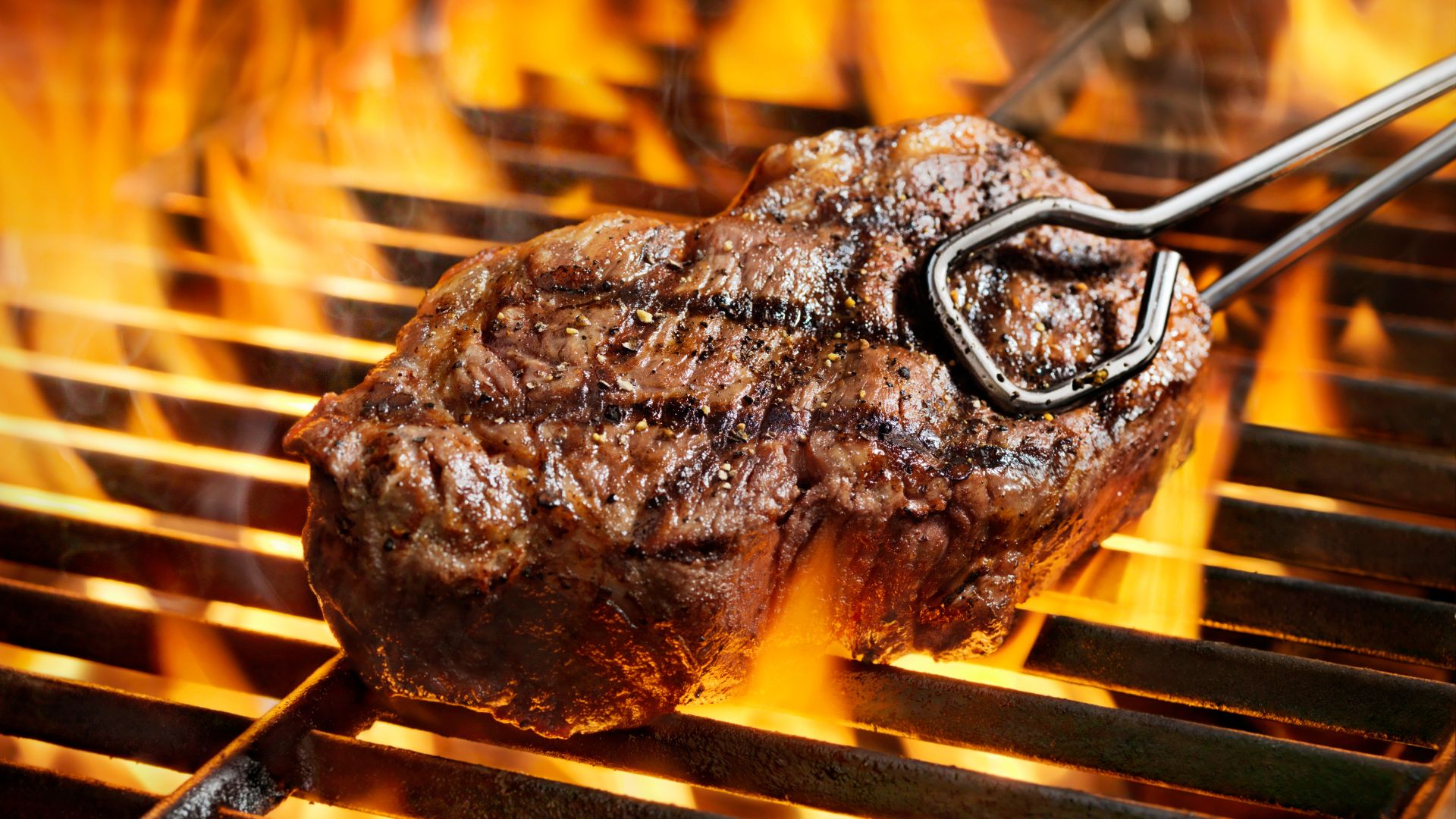 Grilled steak cooking over open flames on a barbecue
